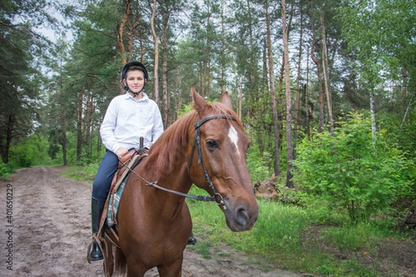 Fototapeta On a sunny summer day in the forest, a boy riding a horse.
