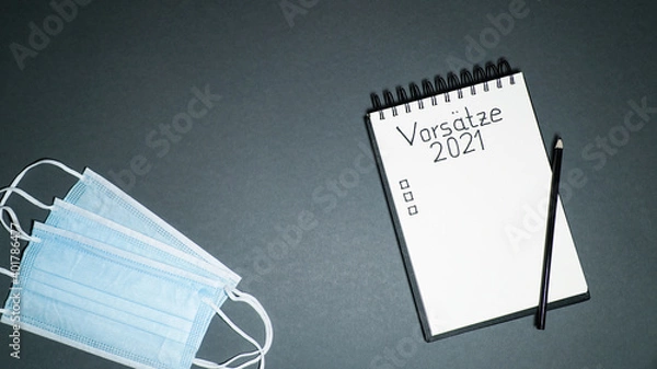Obraz notebook with goal list 2021 an coronavirus face mask on dark background with german language