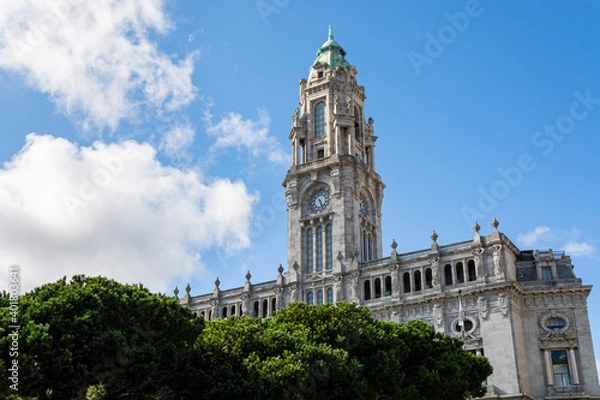 Fototapeta Porto City Hall. Old building with tower and clock. Pine trees in the foreground. Blue sky with clouds.