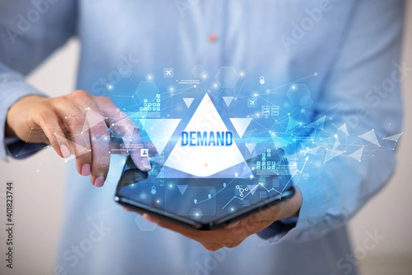 Fototapeta Businessman holding a foldable smartphone with DEMAND inscription, business concept