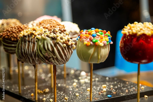 Fototapeta Various candied caramel apples on a stick standing in a street food shop on christmas fair