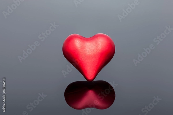 Fototapeta volumetric symbol of a heart of red on a black background with reflection, a symbol of health and love on the medical theme of celebrating Valentine's Day.