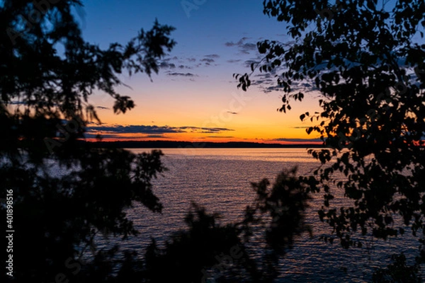 Obraz Torch lake Michigan sunset looking through trees.