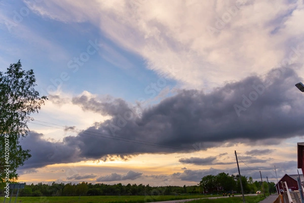 Fototapeta A beautiful landscape of a weather front drifting across Cheltenham at sunset, blue sky with massive clouds
