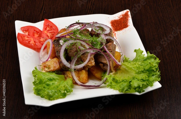 Obraz fried pieces of potato and beef sprinkled with onions and dill with salad, spices and tomatoes