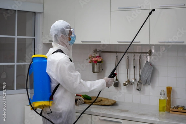 Obraz health care worker in white jumpsuit and protective face mask using spraying machine to disinfect virus pandemic.  Health care and midicine concept. New normal social distancing concept.