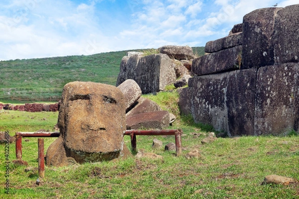 Fototapeta Moai head and stone structure at the ceremonial center of Vinapu, on Easer Island - Rapa Nui, against a blue sky covered by white clouds.
