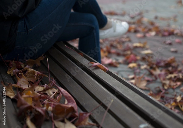 Fototapeta A man sits on a bench in an autumn park.
