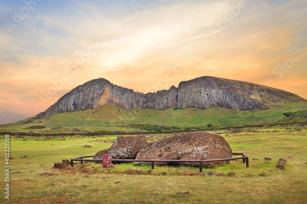Fototapeta Fallen Moai statue at the Ahu Tongariki ceremonial center on Easter Island, covered by a colorful sunset sky, against the crater of the Rano Raraku volcano.