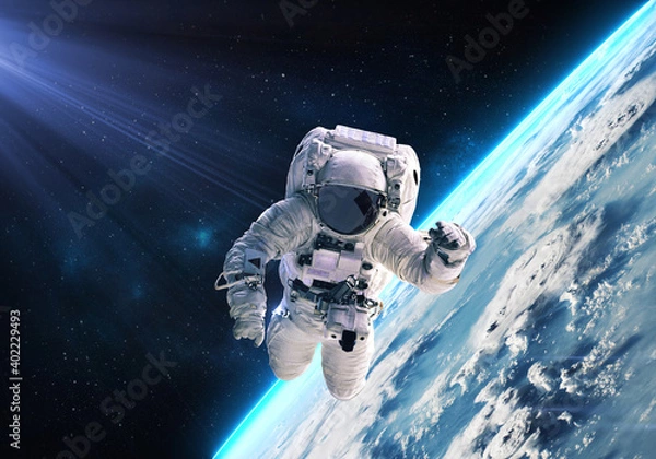 Fototapeta Science fiction walpaper of a lonely astronaut in free spacewalk orbit Earth planet globe with glow and nebulae on the background. Elements of this image furnished by NASA