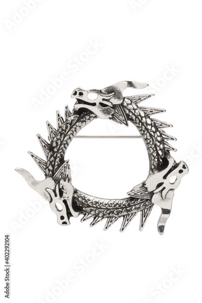 Fototapeta Detail shot of silver brooch made as triple Uroboros - three dragons biting each other's tails. The elegant jewelry in gothic style is isolated on the white backdrop. 