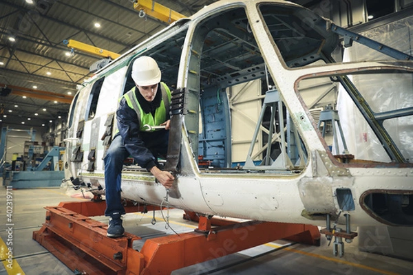 Fototapeta Portrait of a Caucasian man , factory engineer in work clothes controlling the work process at the helicopter manufacturer. 