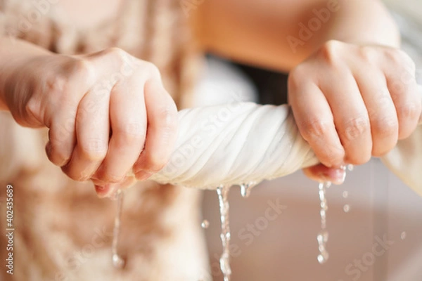 Fototapeta Two woman hands wring wet cloth after washing by twist and squeeze. Housework ,laundry and optimization concept ,selective focus on hand on the left