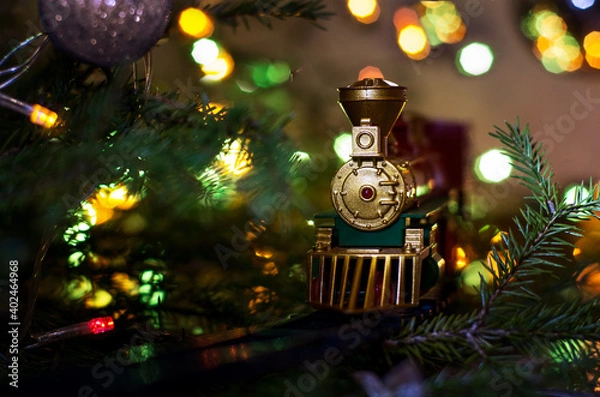 Fototapeta toy train rides on the Christmas tree. on the Christmas tree lights garland