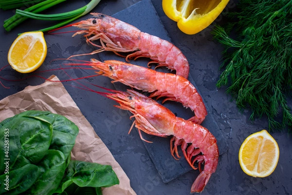 Obraz Large langoustines shrimp on a black stone on the black kitchen table. Seafood for a healthy diet. Ingredients. Top view.