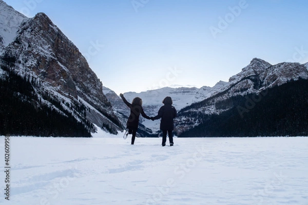 Obraz Lake Louise, Canada - december 2020 : Back view of a couple standing in the snow on the frozen lake 