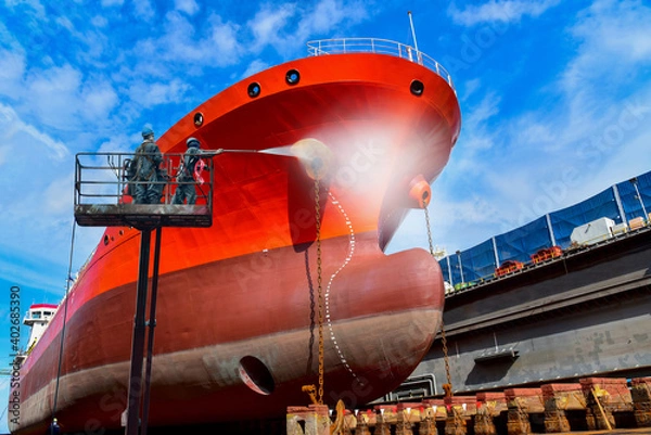 Obraz Washing and Cleaning in shipyard Worker in floating dry dock with water jet cleans the shipboard and have movement of people of the ship from sea vegetation before sandblast and paint