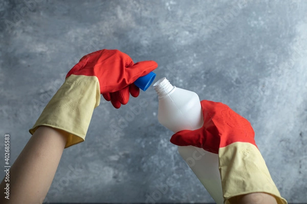 Obraz Hands in red gloves opening container of bleach