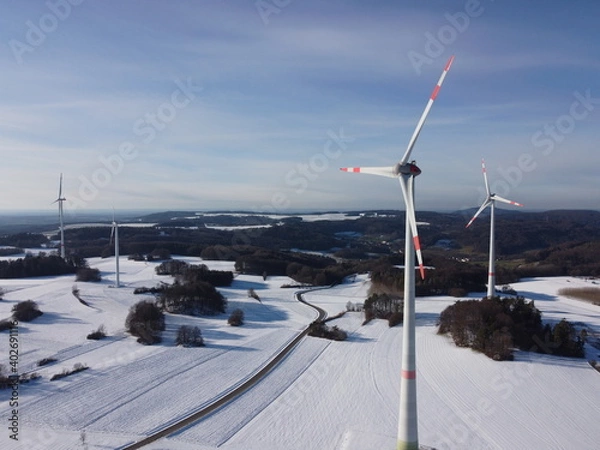 Fototapeta Aerial view of a wind farm in a winter landscape during sunset. Aerial view of wind turbines during sunset.