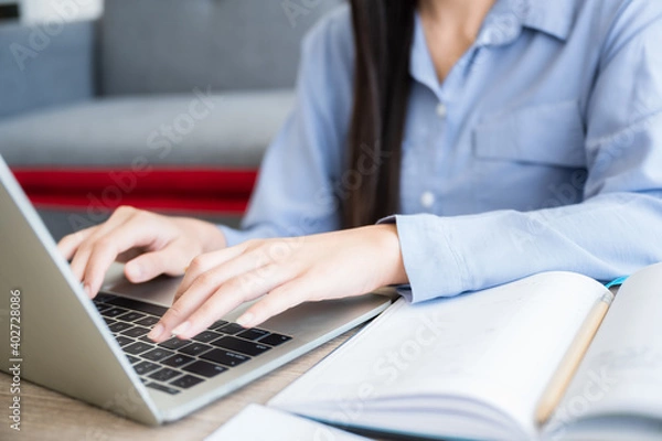 Fototapeta Business woman working from home by computer laptop. Close up and focus to keyboard and her hand.