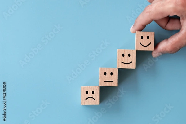 Fototapeta Close up top view customer hand choose smiley face on wood cube, Service rating, satisfaction concept.