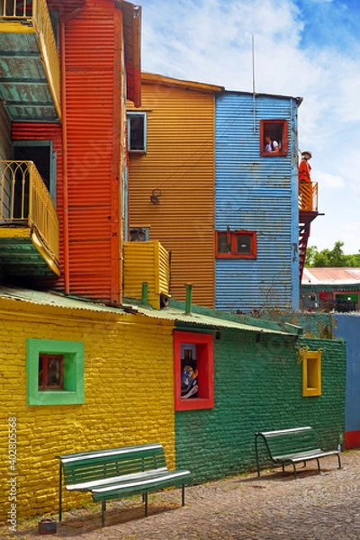 Fototapeta Vertical view of colorful buildings in Caminito of the Argentinean district La Boca, in Buenos Aires, with vintage walls against a blue sky.