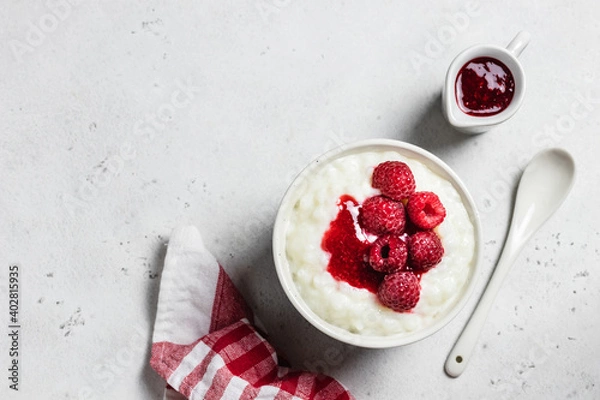 Fototapeta Almond milk rice pudding with raspberry sauce  in a bowl. Top view, space for text.