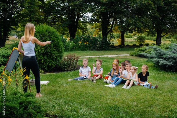 Fototapeta A teacher teaches a class of children in an outdoor Park. Back to school, learning during the pandemic