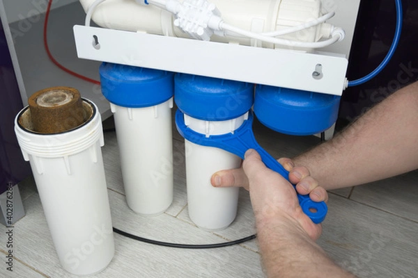 Fototapeta Close-up plumber hand holding used dirty rusty first-stage filter for drinking water. Changing cartridge of home sanitary equipment filtration system