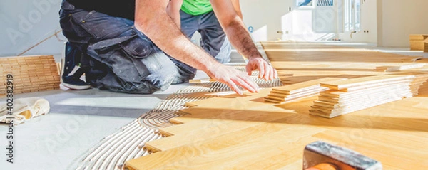 Fototapeta worker installing oak herringbone parquet floor during home improvement