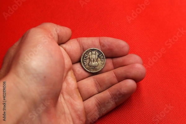 Fototapeta Old coin from India in hand on red background