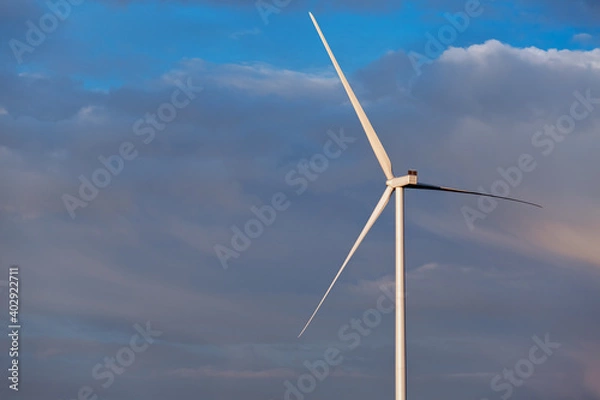 Fototapeta wind turbine offshore windmill of white color made of iron with blades against a blue sky with clouds, alternative electricity preserving nature.