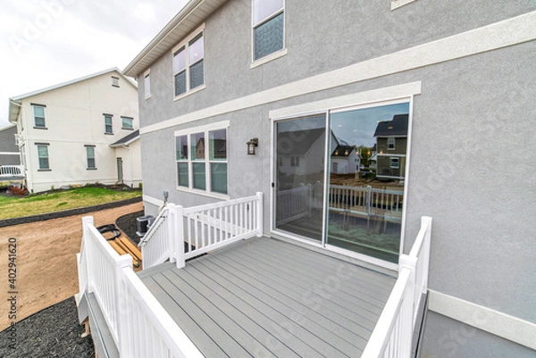 Obraz Deck of two storey house with sliding glass door and stairs leading to yard