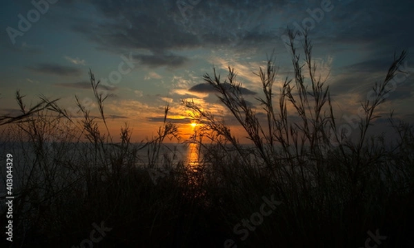 Fototapeta A relaxing photo of sunset whose lights are reflected in the sea and spread through the cloudy sky.