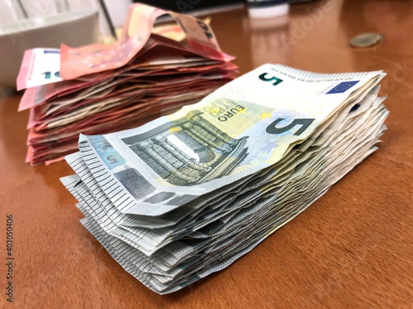 Fototapeta Stacks of 5 an 10 Euro notes on a table