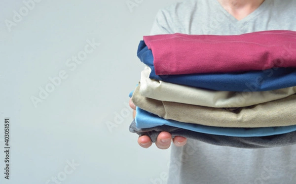 Obraz Close-up of a man without a face stretches his arms forward with a stack of clothes