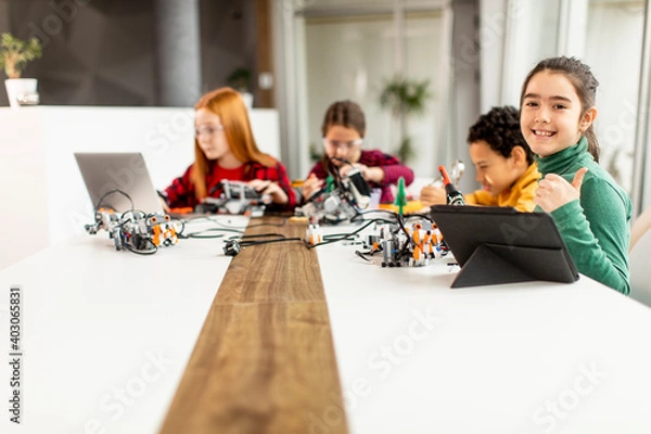 Fototapeta Happy kids programming electric toys and robots at robotics classroom