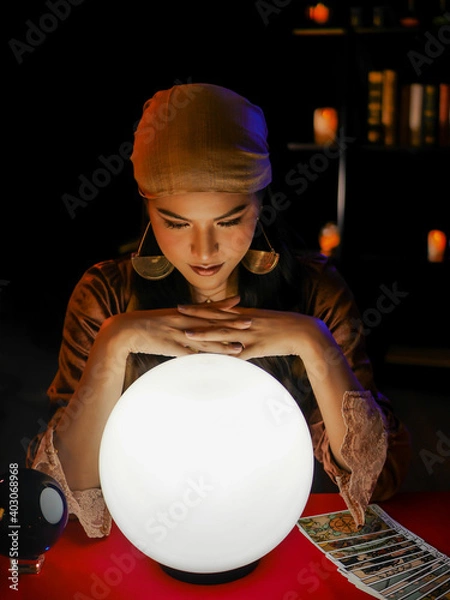 Obraz Asian woman fortune teller using magical occult divine power crystal call to forecast luck on red table. 