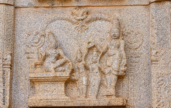 Fototapeta Hampi, Karnataka, India - November 4, 2013: Hazara Rama Temple. Closeup of beige stone damaged sculpture on wall featuring group of royals.