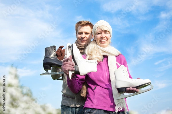 Obraz Ice skating winter couple young woman and man holding ice skates outdoors in snow