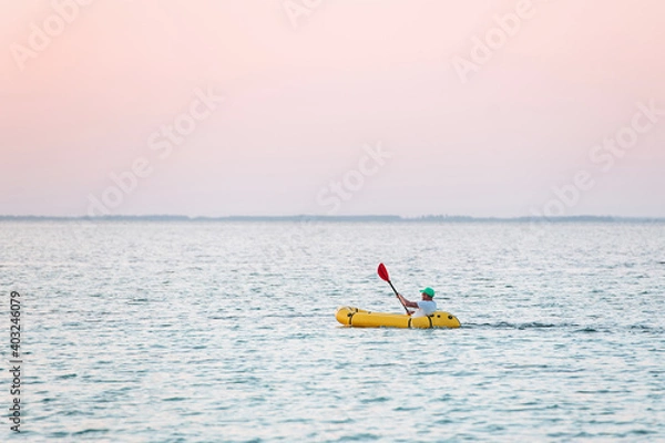 Fototapeta Distant view of man in the yellow colored boat that is in the sea