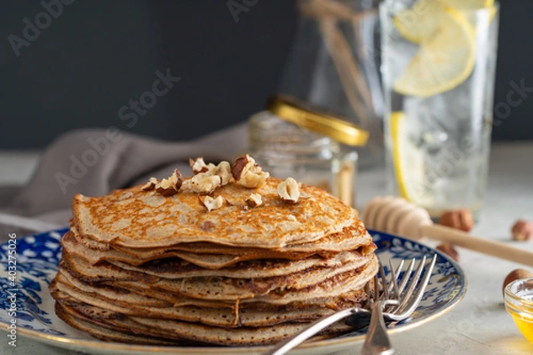 Fototapeta buckwheat pancakes with honey and hazelnuts on an old plate