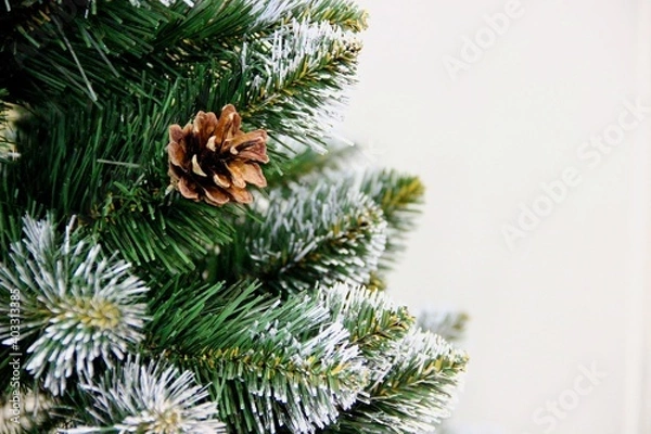 Obraz a fir cone on a green with a white touch of artificial pine branch, a place for text on the right. Festive background