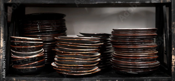 Fototapeta Stacks of craft ceramic or pottery plates on a shelf