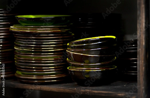 Fototapeta Stacks of craft ceramic or pottery plates on a shelf