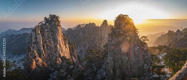 Fototapeta Panorama view of the mountain peaks of Huangshan National park, China. A lot of snow and clouds in the sunrise time with the winter season. Landscape of Mount Huangshan of the winter season.