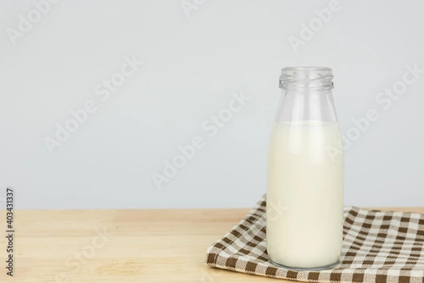 Fototapeta Bottles with fresh milk on a wooden table..Raw milk is high in calcium and protein to drink for all ages..Milk consumption nutritious and healthy dairy products concept.