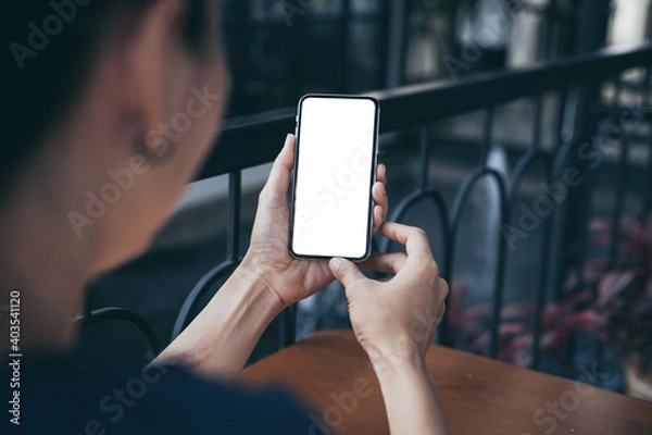 Fototapeta cell phone blank white screen mockup.woman hand holding texting using mobile on desk at office.background empty space for advertise.work people contact marketing business,technology