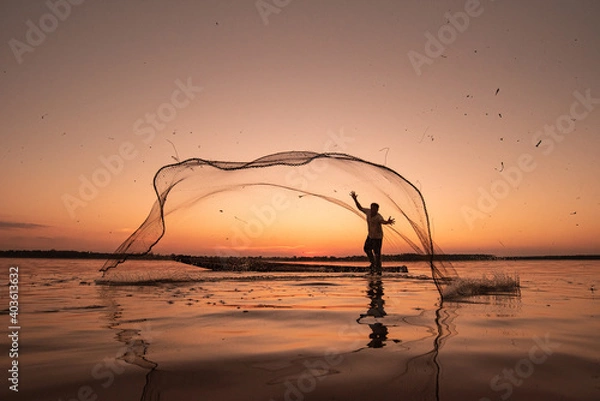 Obraz Asian fisherman on wooden boat casting a net for catching freshwater fish in nature