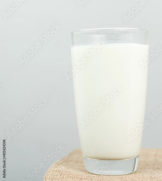 Fototapeta The glass of fresh milk on sackcloth for a background. Raw milk is high in calcium and protein to drink for all ages..Milk consumption nutritious and healthy dairy products concept.